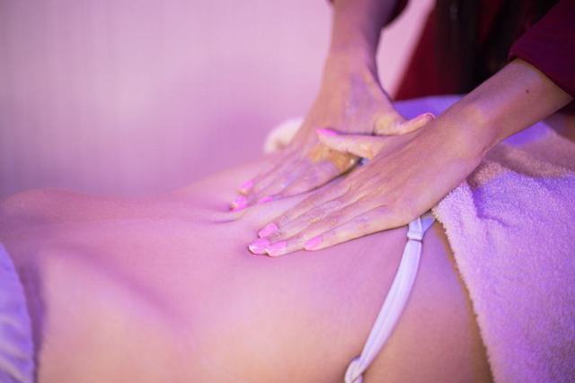 Flacon d'huile végétale et serviette posés sur une table de massage